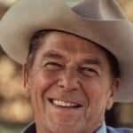 Portrait of a senior man wearing a cowboy hat, smiling warmly outdoors.